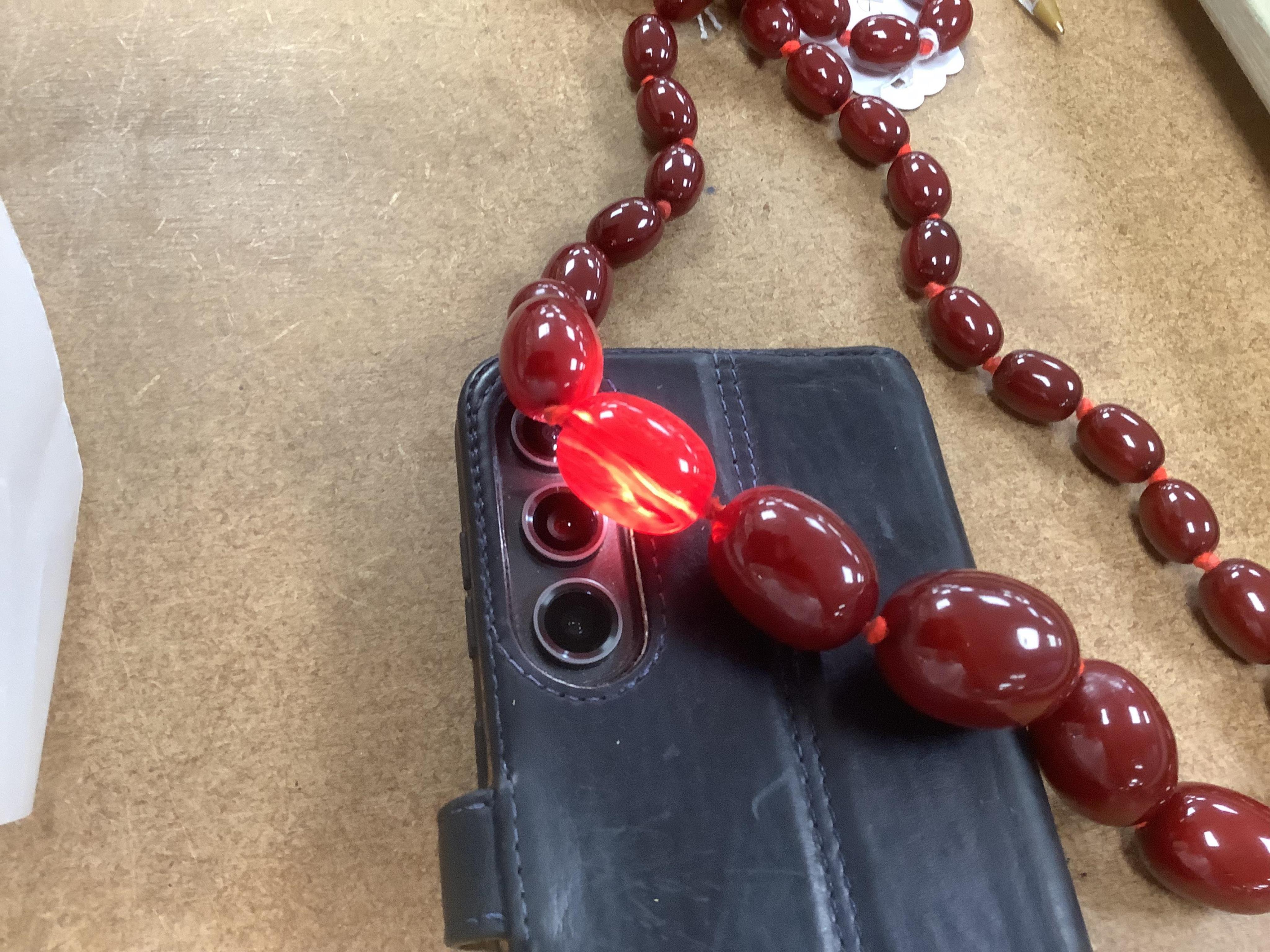 A single strand graduated simulated oval cherry amber bead necklace, 72cm, gross weight 100 grams.